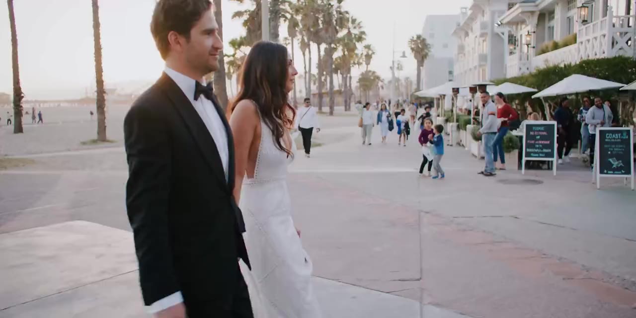 Jeremy and Lauren walking hand in hand on the beach path in Santa Monica